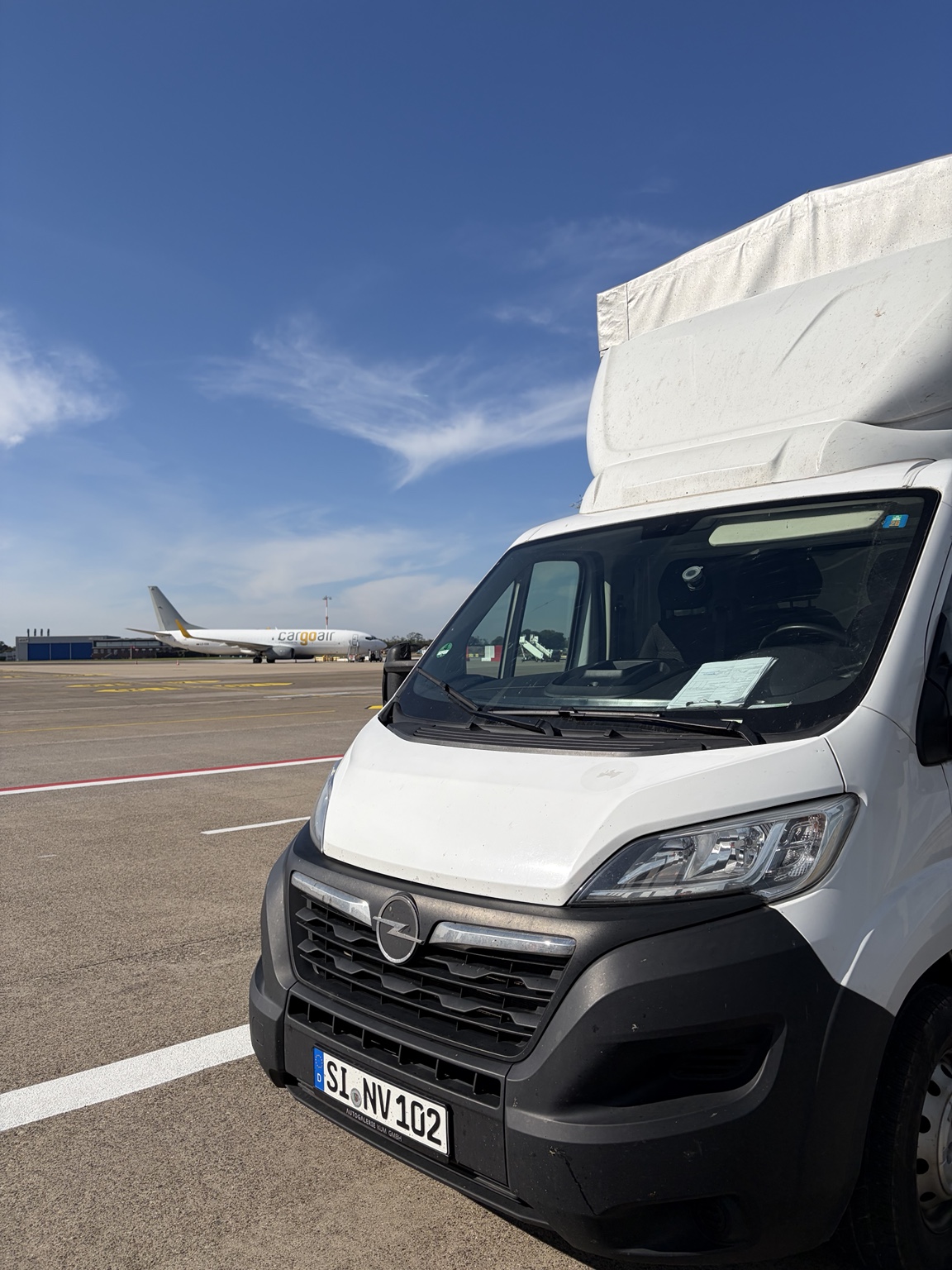 NOVA-Transporter auf dem Flughafenvorfeld neben einem Frachtflugzeug